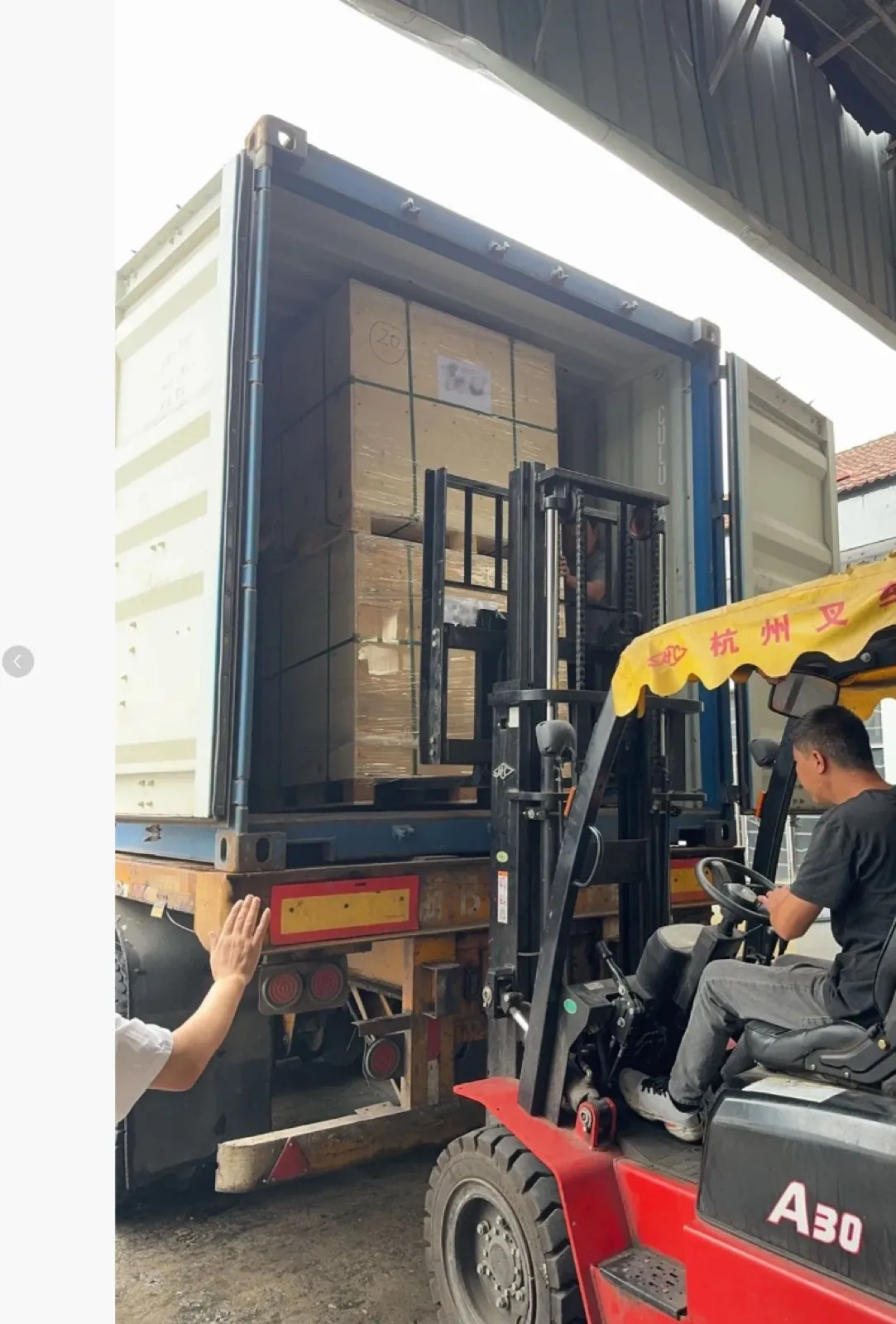 Manipulación de una caja de madera junto a un contenedor